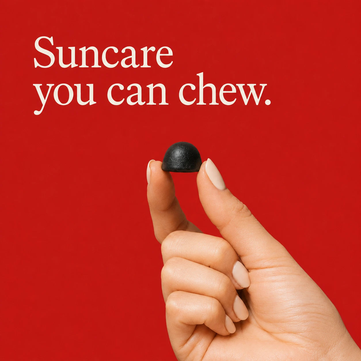Suncare you can chew — a hand holding a single dark berry gummy against a poppy-red background