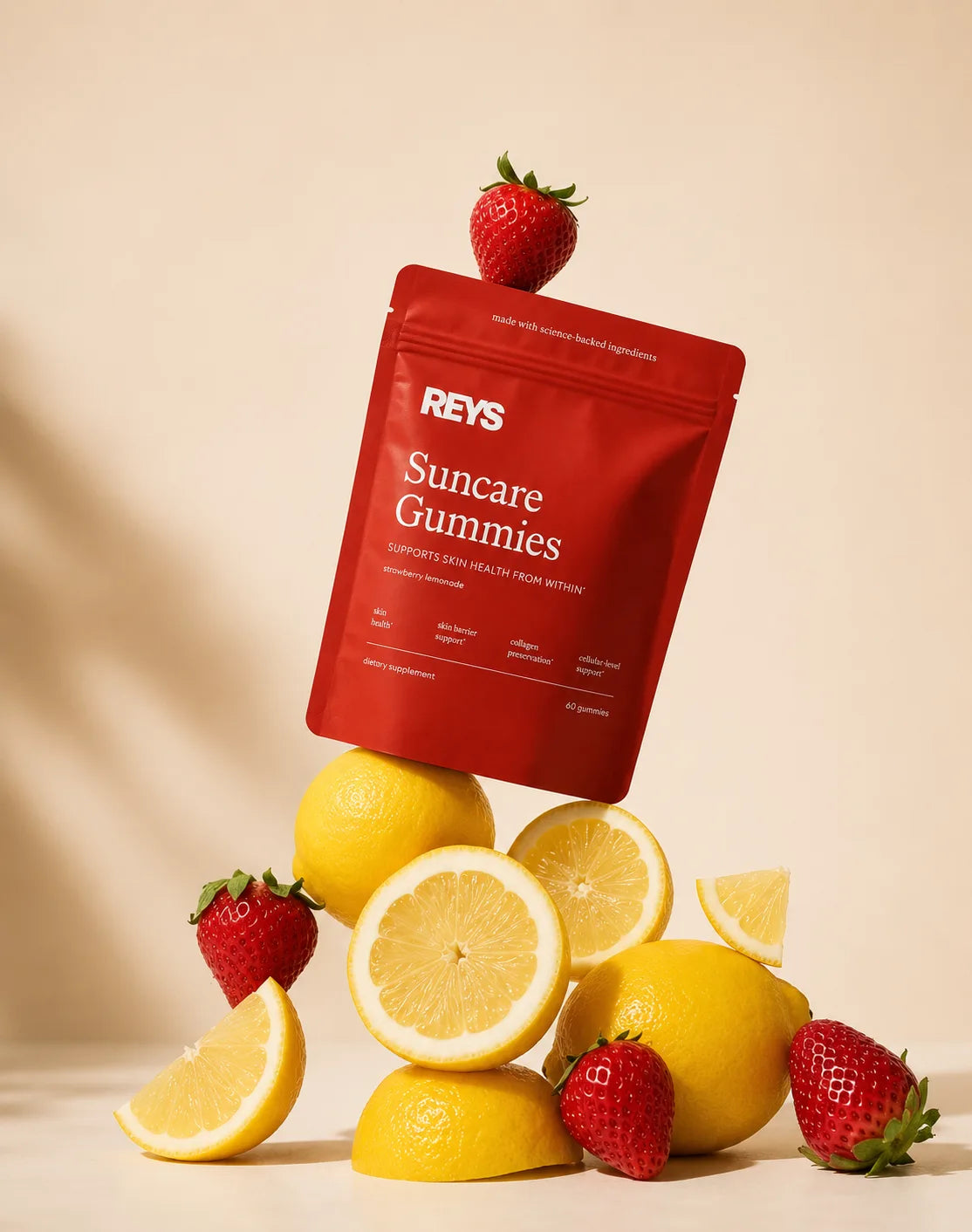 The Suncare Gummies pouch balanced on a stack of fresh lemons and strawberries — strawberry lemonade flavor, made with science-backed ingredients